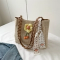 Detail der gewebten Strohtasche mit gelber Blumenverzierung und bedrucktem Seidenschal - Khaki