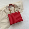Large red vintage shoulder bag with V-quilted texture and gold chain strap on beige blazer - Red