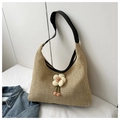 Detail of hand-woven straw shoulder bag featuring a white floral charm and black strap - Black