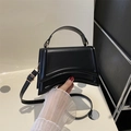Bolso de mano minimalista en cuero negro mate con base curva y correa de hombro ajustable - Negro