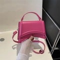 Bolso de mano rosa fucsia con base curva y detalles dorados llevado como bandolera - rosa intenso