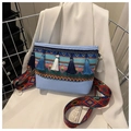 Detalle de bolso bandolera étnico con borlas, bordado colorido y correa ancha con textura - Azul