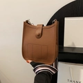 Brown lychee leather shoulder bucket bag with striped strap shown in a hand-held view - Brown