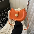 Detail view of bright orange crescent bag with large gold buckle and smooth PU leather - Orange Red