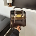 Dettaglio del tessuto scozzese vintage e fibbia in pelle marrone su un mini zaino chic - caffè