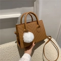 Minimalistische karamellbraune Umhängetasche mit V-Steppmuster und weißem Pompon - Braun