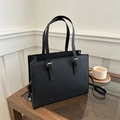 Detail view of black Saffiano leather tote bag featuring adjustable silver buckle straps - Black