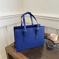 Detailed macro view of navy blue Saffiano leather tote with silver metal buckle detail - Blue