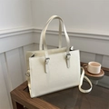 Detailed macro view of cream-colored Saffiano tote bag with silver buckle and crossbody strap - White