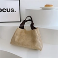 Dettaglio della borsa tote in paglia intrecciata con manici marroni su base sobria - Cachi con manici marroni