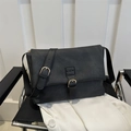 Bolso bandolera retro negro mate con hebilla dorada en una silla moderna - Negro