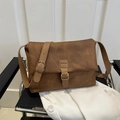 Bolso mensajero vintage marrón para mujer con correa ajustable sobre una silla - Marrón Oscuro