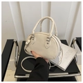 Dettaglio della mini borsa Boston color crema minimalista sulla sedia di pelle nera - Bianco Con Pendente