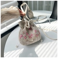 Detalle del bolso tipo cubo de paja con bordado floral y elegante cordón de perlas - Rosa oscuro