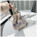 Detalle de bolso saco de paja con bordado floral y cordón ajustable con perlas - Morado
