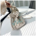 Detalle del bolso de cubo tejido beige con bordado floral azul y cordón con perlas - Verde