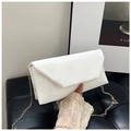 Gros plan du sac bandoulière blanc à motif crocodile avec chaîne dorée sur canapé - Blanc