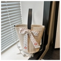 Detail der gewebten Stroh-Eimertasche mit schwarzem Ledergriff und floralem Seidentuch - Schwarz