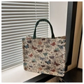 Close-up of butterfly print tote bag with woven jacquard texture and green fabric handles - White