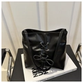 Detail of black leather tote bag featuring a decorative bow and silver eyelets on a stand - Black