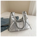 Borsa tote argento con fiocchi e cerniere verticali su sfondo di biancheria bianca - Argento