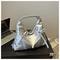 Bolso hobo plateado con cremalleras y lazos decorativos sobre mesa de madera - Plateado