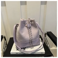 Detail of lavender drawstring bucket bag with chain link on modern architectural books - Purple
