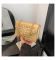 Detail van gouden crossbodytas met krokodillenreliëf, S-logo en metalen kwastje - Goud