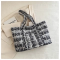 Grand sac cabas en tweed à carreaux noir et blanc posé sur un blazer beige élégant - Noir