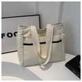 Dettaglio della borsa tote minimalista in tela crema con tasca laterale e cinturini - Bianco