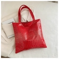 Detail shot of bright red crocodile-embossed tote bag texture on a white blazer - Red