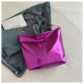 Close-up of metallic purple tote bag with silver chain strap on denim jacket - Purple
