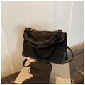 Detail of black pleated suede handbag showing woven handle and metallic ring connectors - Black
