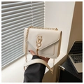 Primo piano della borsa a tracolla beige con patta a V e fibbia dorata a forma di S - Bianco