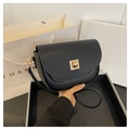Close-up of black leather saddle bag featuring a gold geometric buckle on a white box - Black