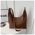 Detailed close-up of brown leather tote bag featuring vertical stitching and gold metal zipper - Brown