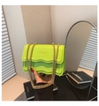 Bolso de cuero verde neón con borde ondulado y cadena dorada sostenido en mano - Estilo de Borde Ondulado / Verde