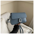 Close-up of matte dusty blue leather crossbody bag with elegant silver U-shaped metal lock - Blue