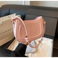 Detalle de bolso media luna rosa claro con líneas en U y elegante embalaje de regalo de lujo - Rosa