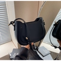 Detalle del bolso de media luna negro con herrajes dorados y costura decorativa en forma de U - Negro