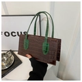 Detail of a dark brown crocodile embossed leather handbag with green top handles - Brown