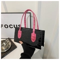 Detail of glossy crocodile pattern black handbag with pink handle in a modern setting - Black