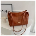Dettaglio della borsa tote marrone vintage con barra metallica dorata e finitura lucida - Marrone