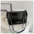 Dettaglio di una borsa tote nera in pelle stropicciata con finiture dorate e doppi manici - Nero