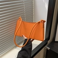 Minimalist orange shoulder bag with knotted strap and gold fashion lettering on front - Orange