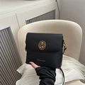 Black bucket crossbody bag featuring a golden bear emblem and sleek faux leather finish - Black