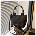 Detalle de textura de cuero negro arrugado en un bolso cubo con estampado y nudo decorativo - Negro