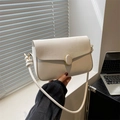 Chic beige crossbody flap bag with matte gold buckle and knot strap detail in sunlight - White