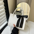 Chic white woven tote bag featuring a large black satin bow and golden rivet details - White