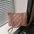 Pink quilted tote bag with gold chain strap placed on a white windowsill - Pink